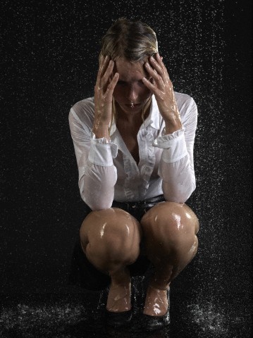 Frustrated business woman in rain --- Image by © Walter Zerla